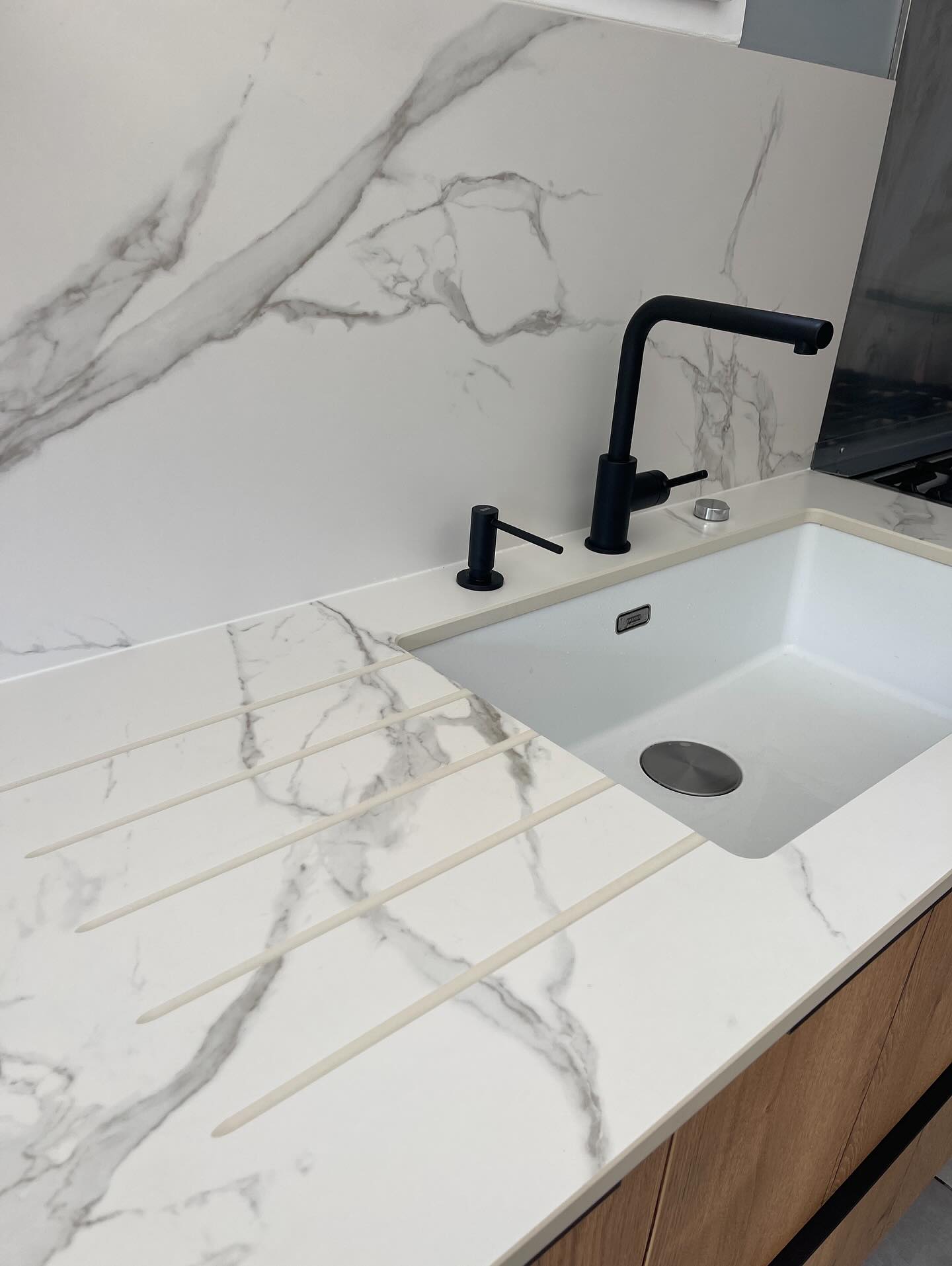 Cette jolie réalisation en Chêne Naturel avec poignée intégrée Graphite brosse, plan de travail et crédences en DEKTON AURA